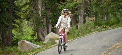 Woman riding an Optibike onroad in a pine forest