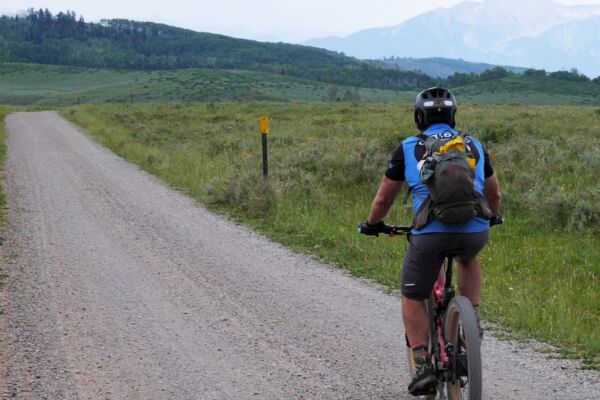 R22 Everest Mountain Road An Optibike R22 Everest rides down a gravel road, you can see snow capped mountains off in the distance