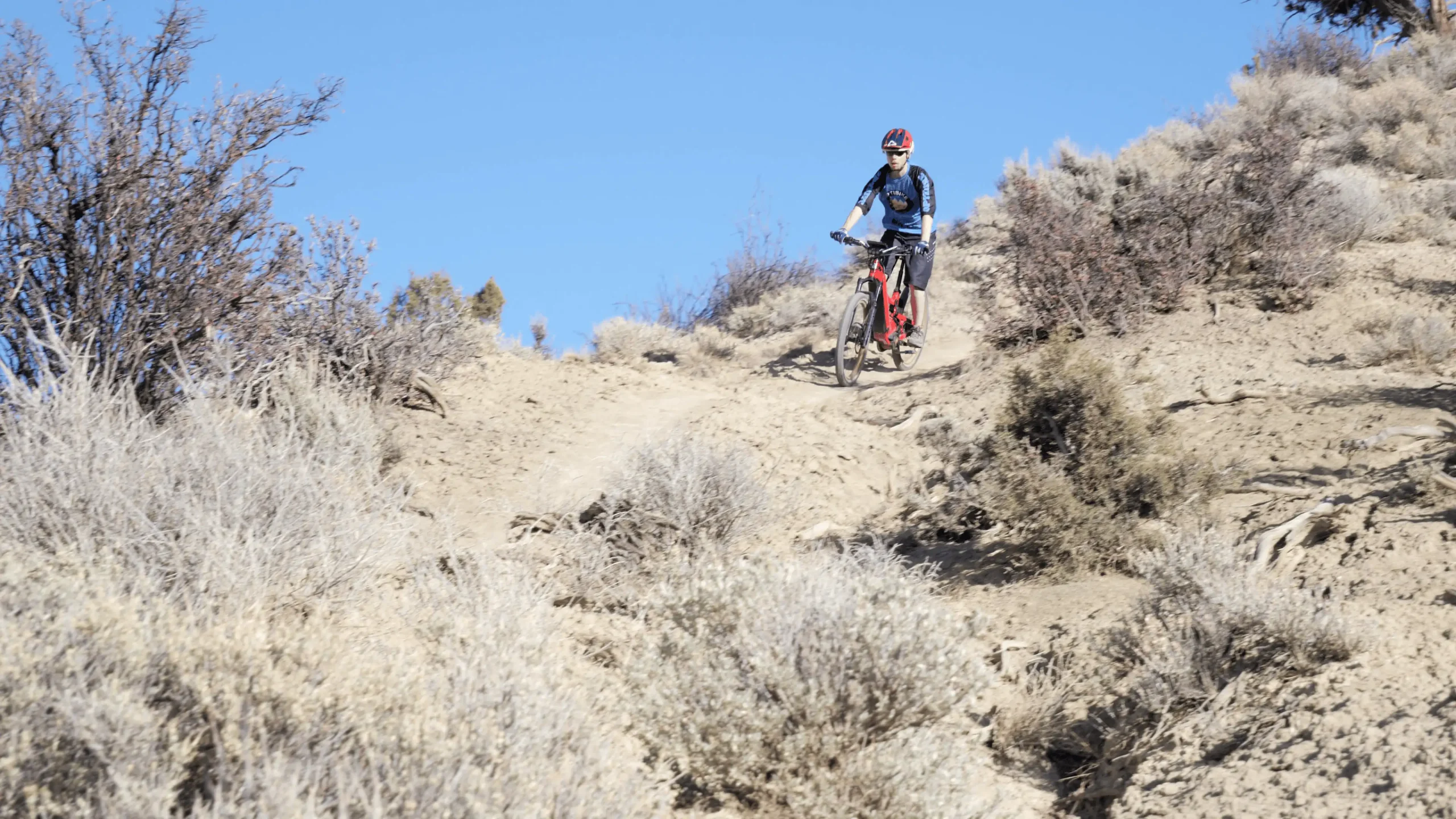 Mountain biker descending a dry desert trail