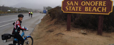San Onofre state beach sign with Tric and her Optibike